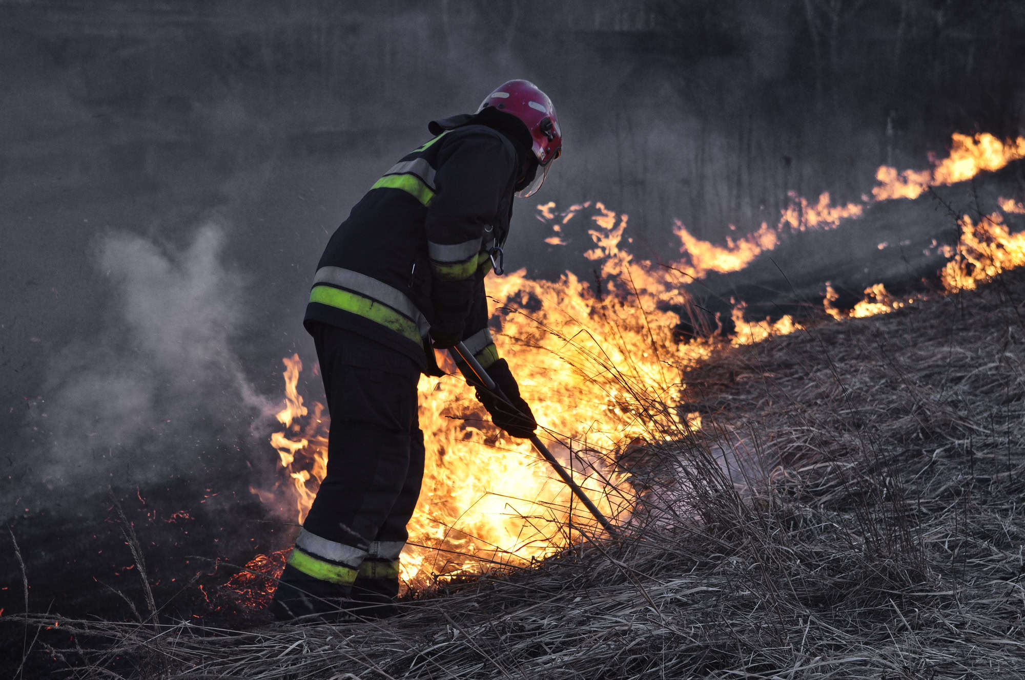 Fireman putting out fire in a meadow.