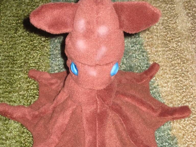 A plush toy representation of a vampire squid, with a deep red color and blue eyes, resembling the mysterious deep-sea creature