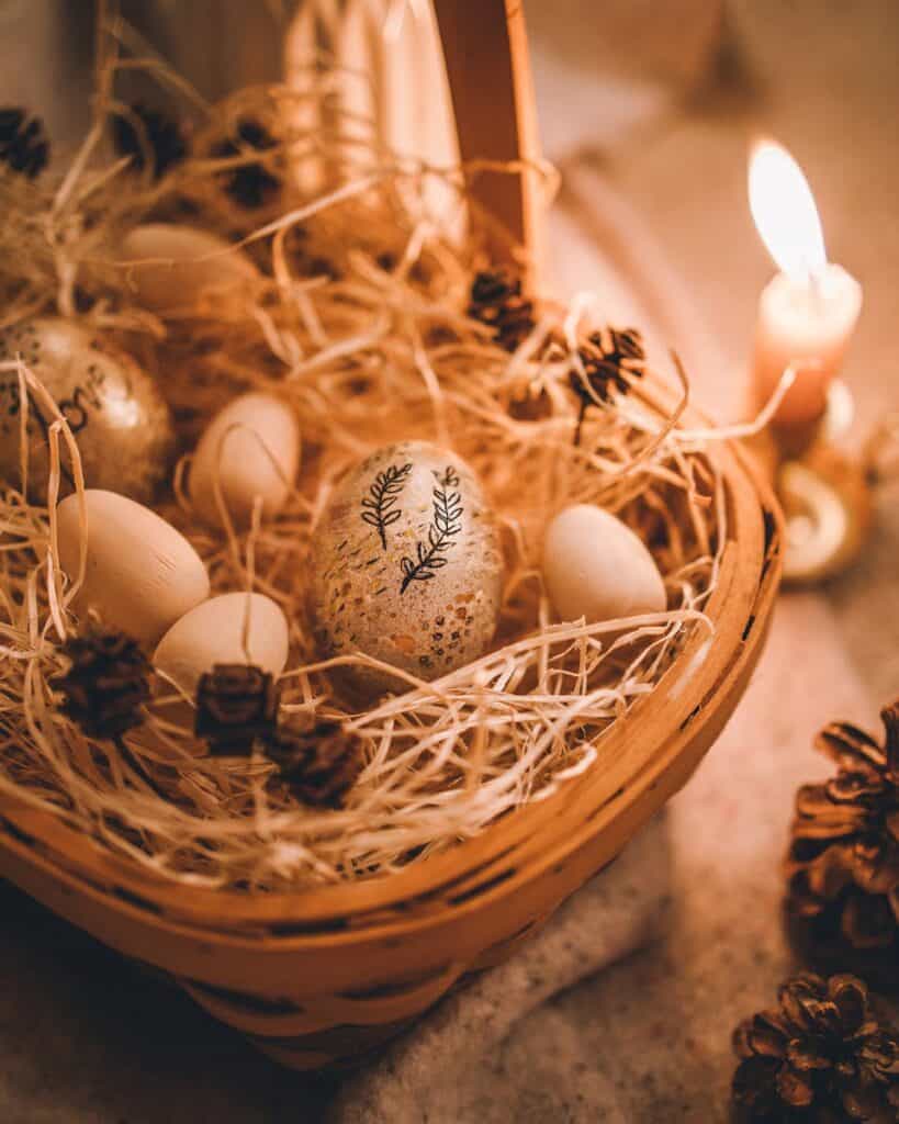 A cozy boho-style Easter basket filled with decorated eggs, lit by candlelight creating a warm ambiance.