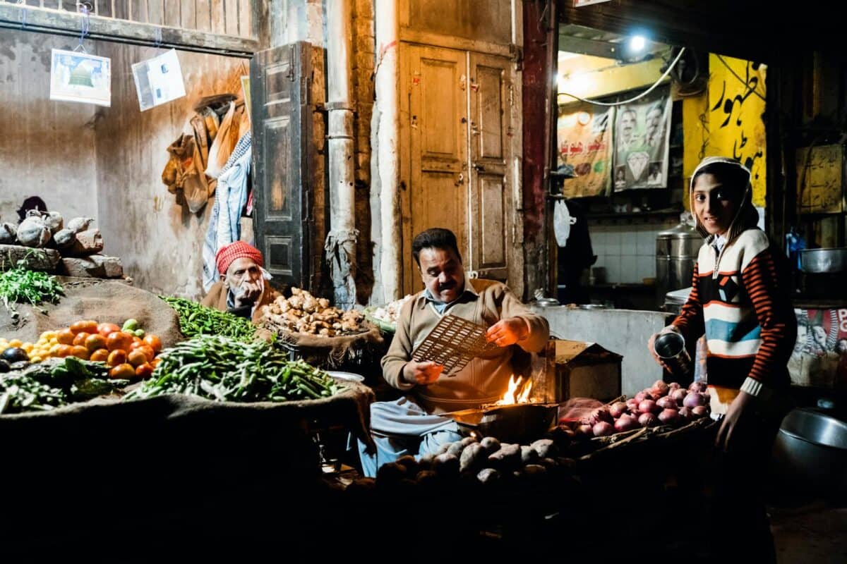 Lively scene at a night market in Faisalabad, showcasing vegetable stalls and local vendors.