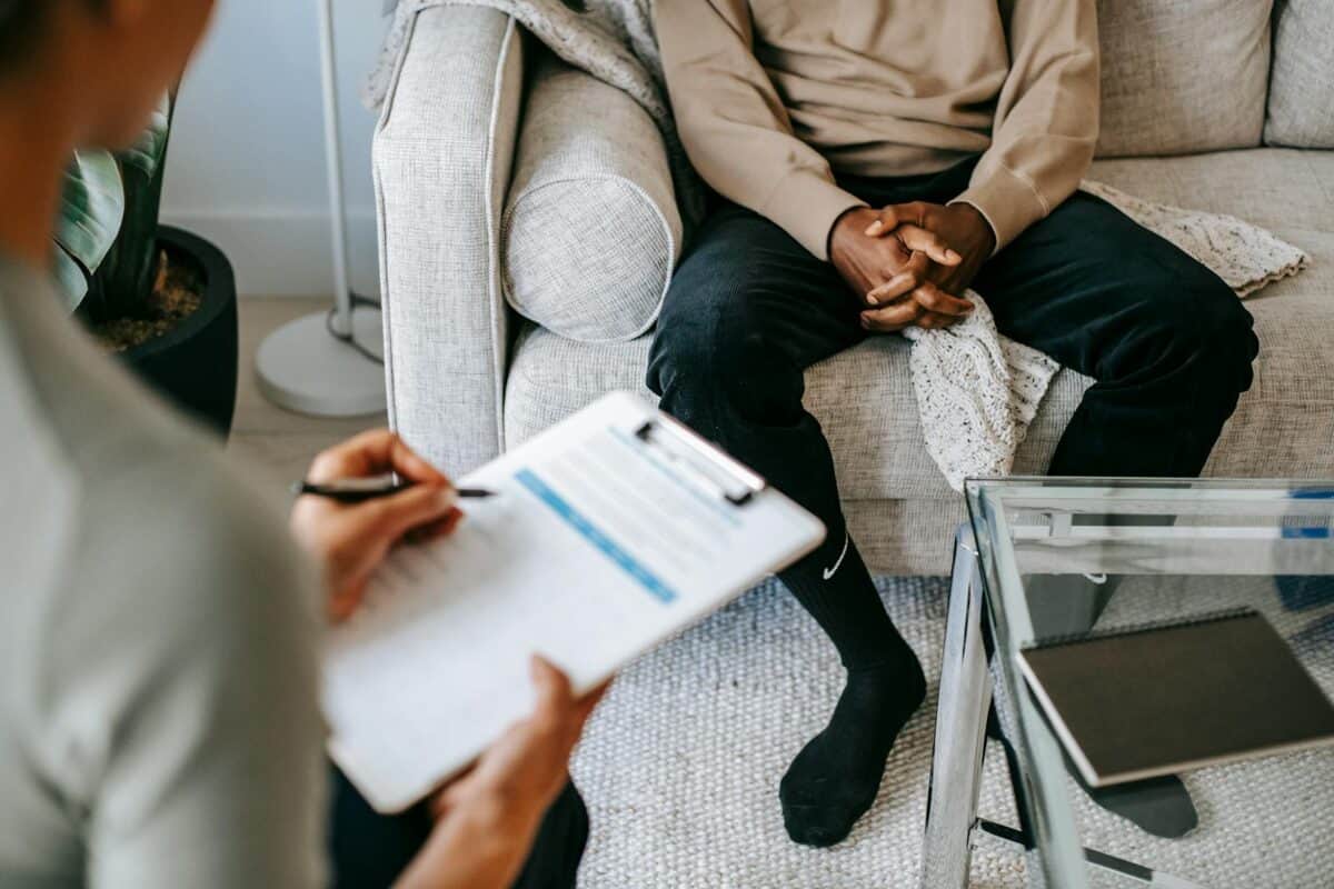 Therapist takes notes as client sits on a sofa