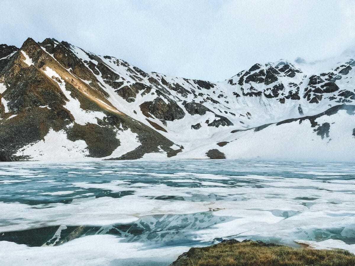 Stunning frozen lake surrounded by snow-capped mountains, capturing the serene winter landscape.