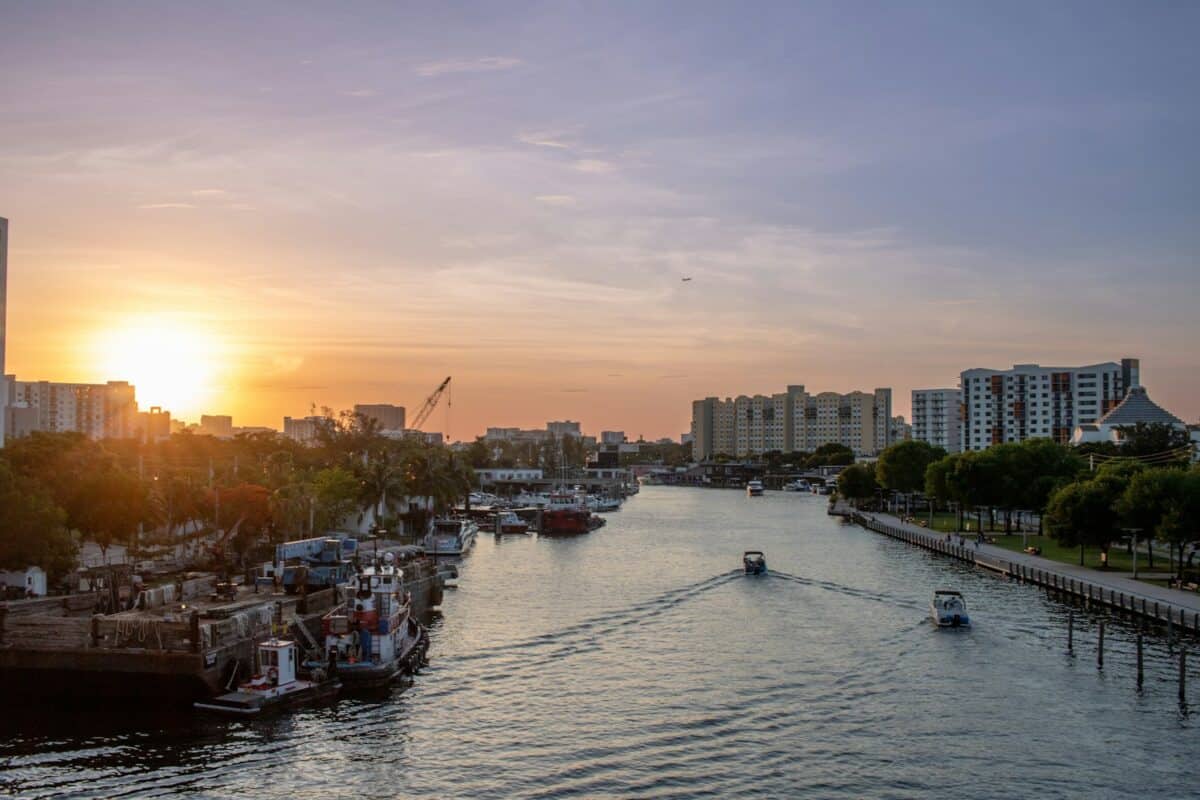 The sun is setting over a river with boats in it