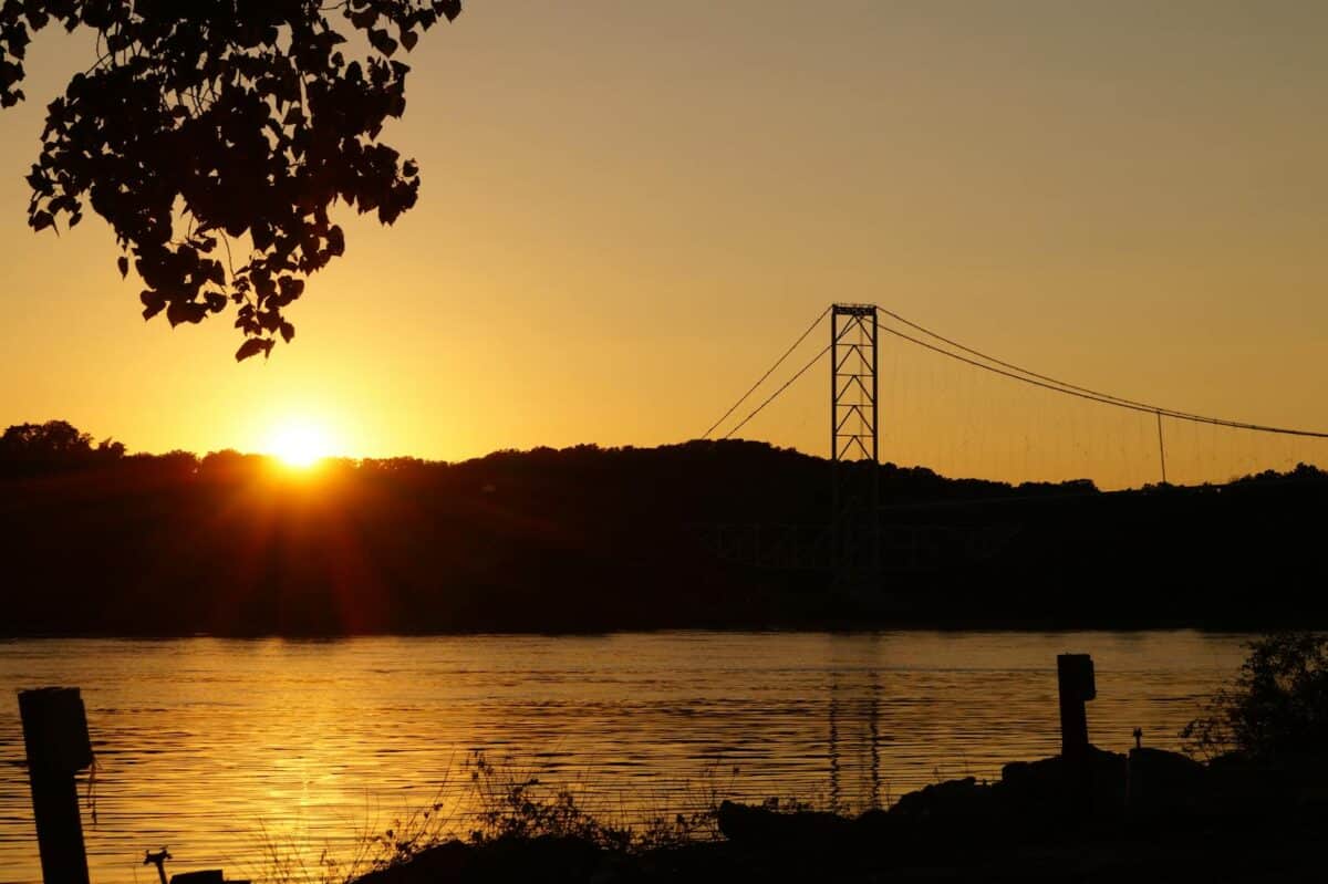 Beautiful sunset view over a suspension bridge in St. Louis, Missouri with reflections on the water.