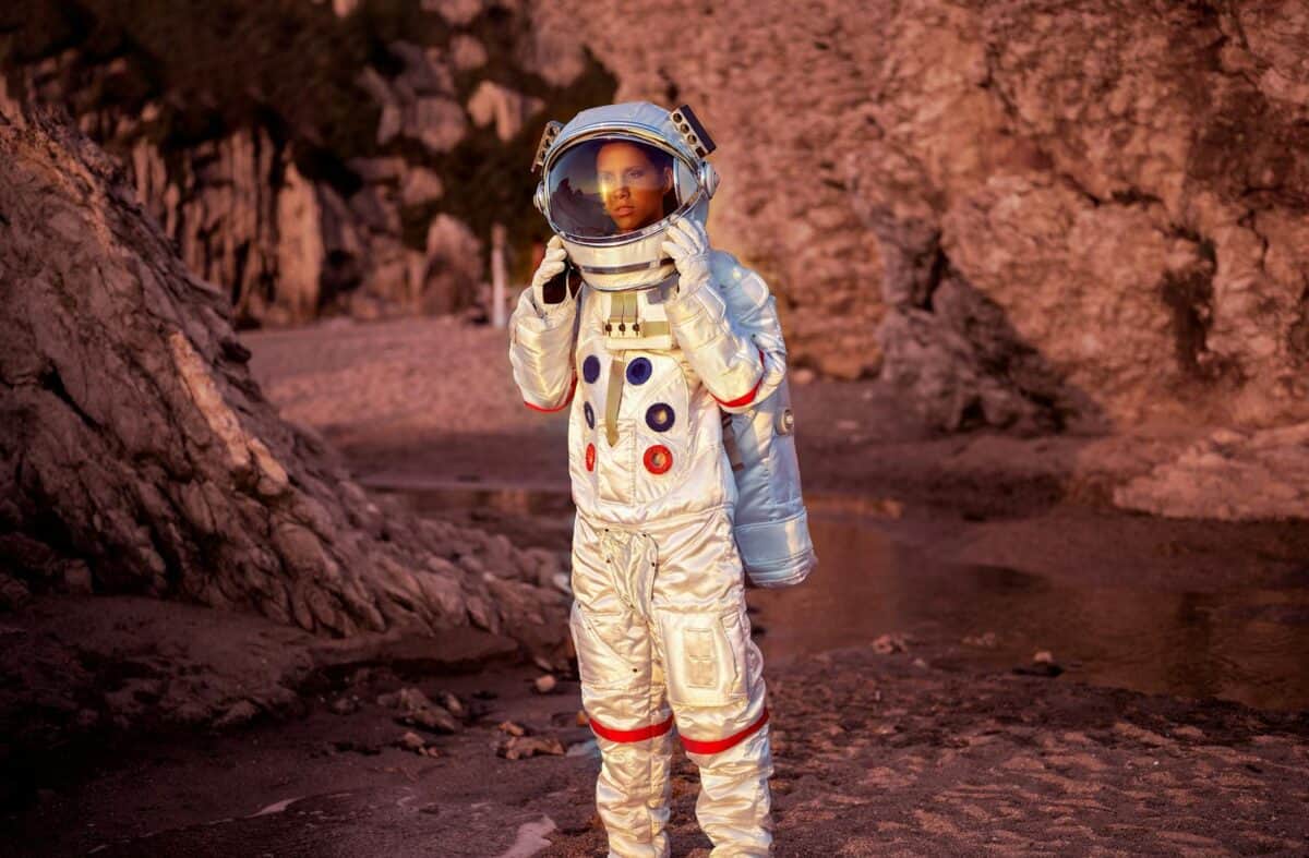 Astronaut in a space suit explores a rocky desert environment at sunset.