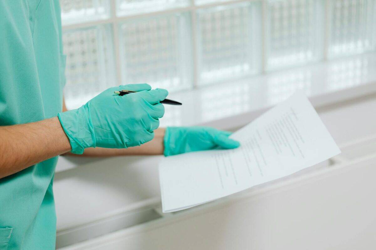 Close-up of a healthcare professional in gloves holding and reading a medical document indoors.