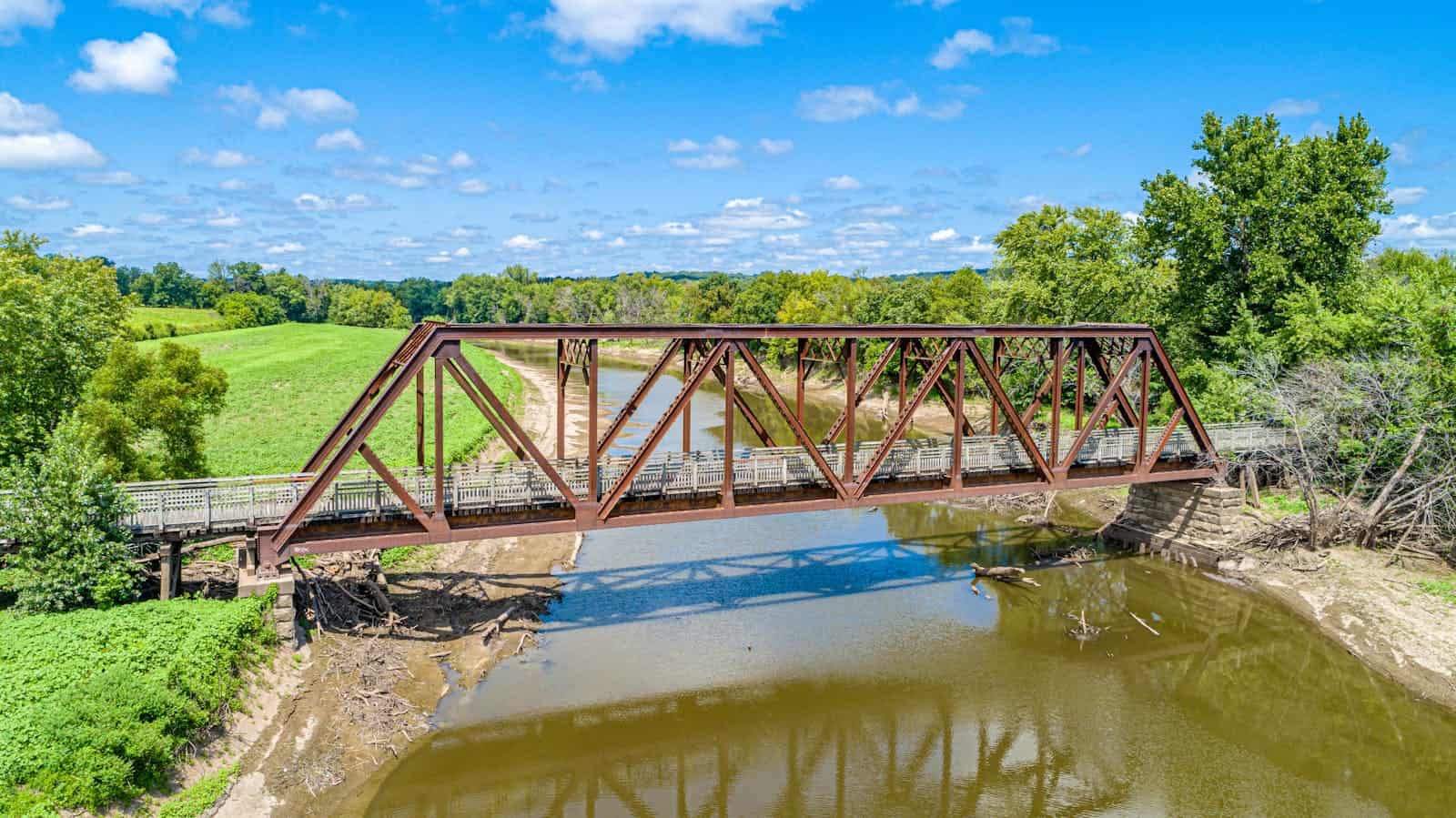 Aerial view of a rustic bridge spanning a river surrounded by lush greenery in Stockton, Missouri.