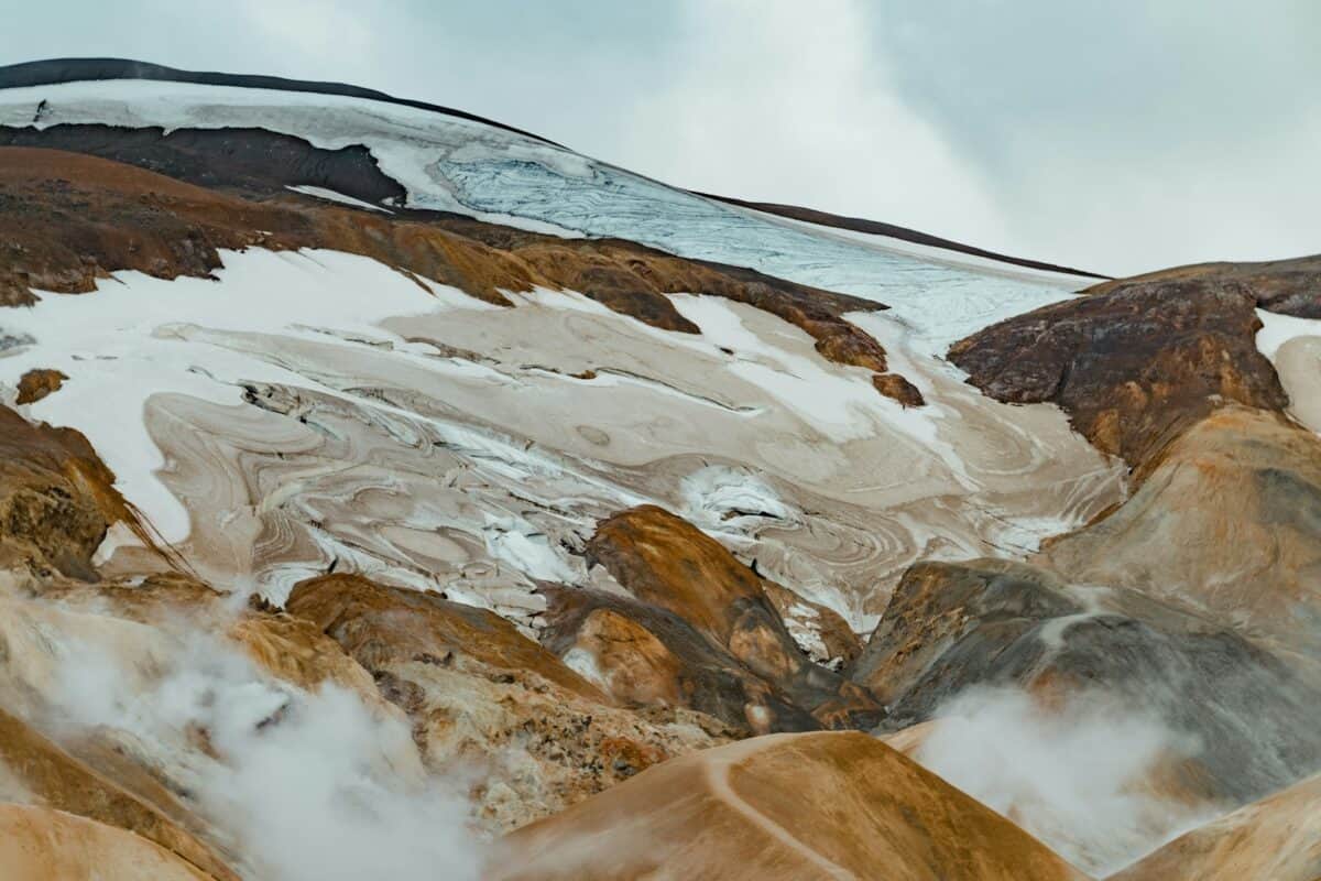A mountain covered in snow and clouds under a cloudy sky