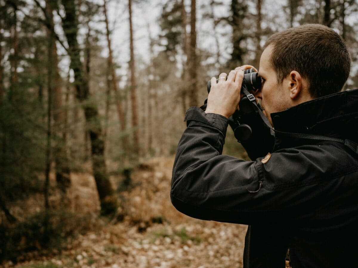 A man using a pair of binoculars to spot birds.