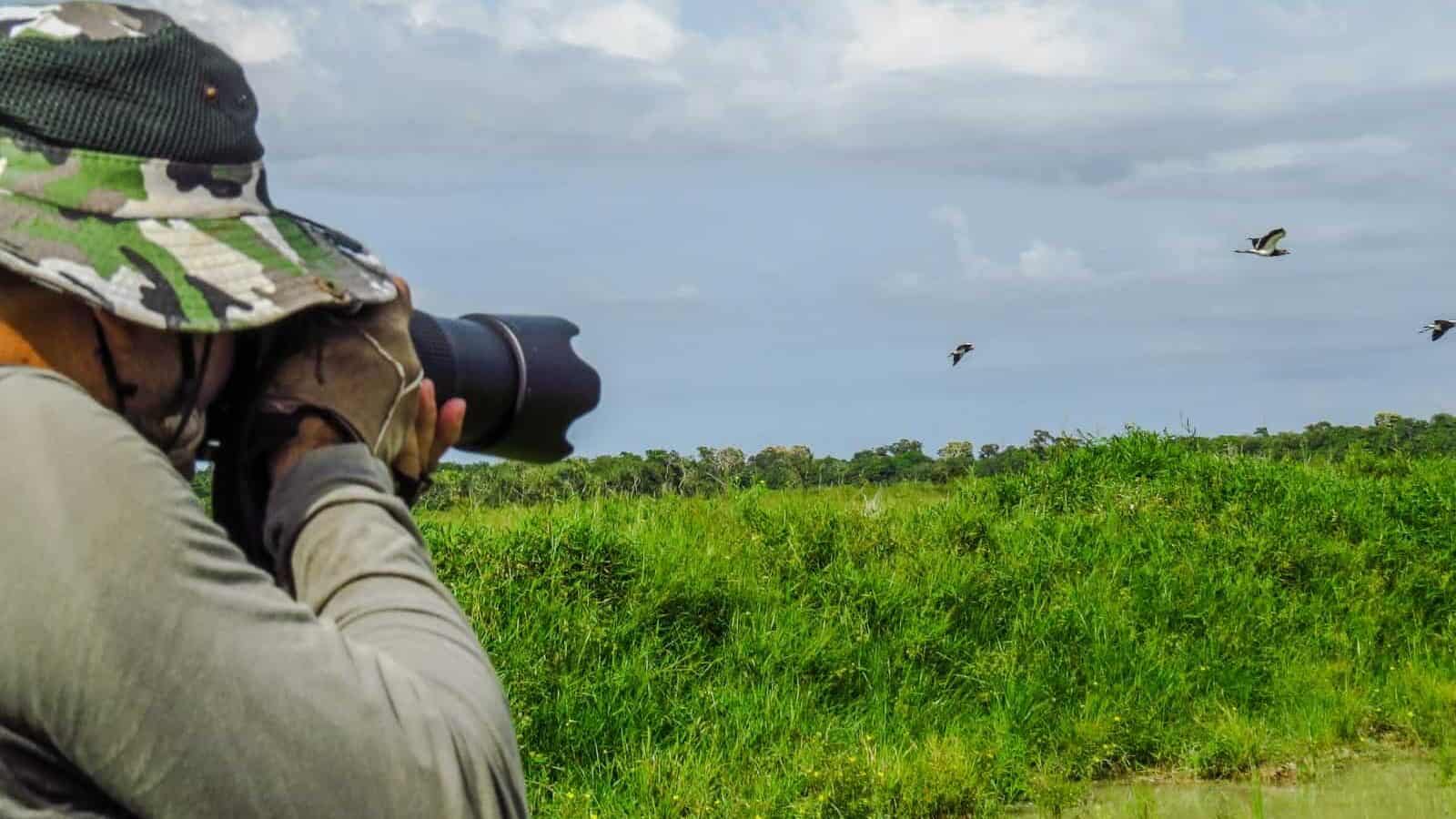 man in gray jacket and black pants taking photo of green grass field during daytime