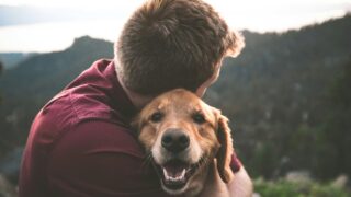 A pet lover embracing his dog.