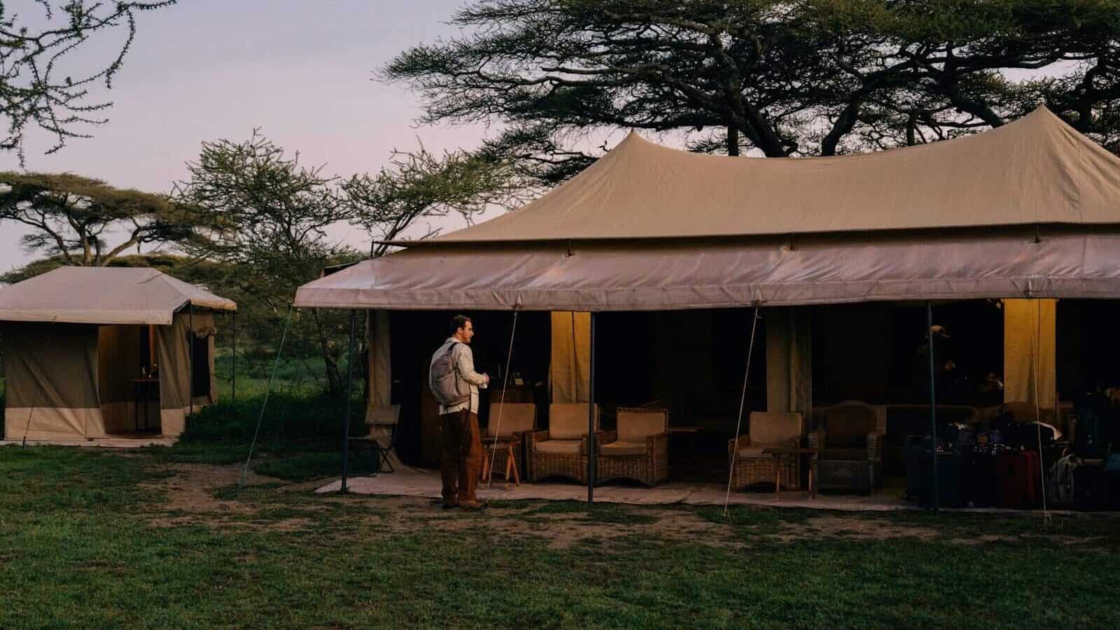 Person standing near a tent in an african safari.
