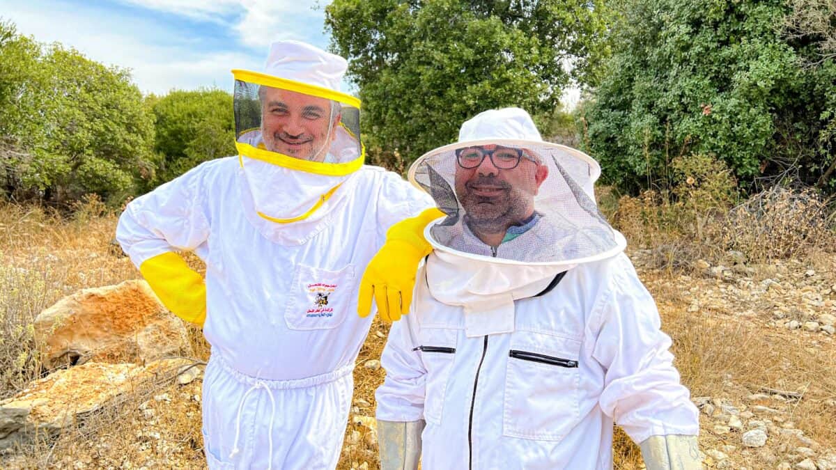 Two men wearing protective gears against insects.