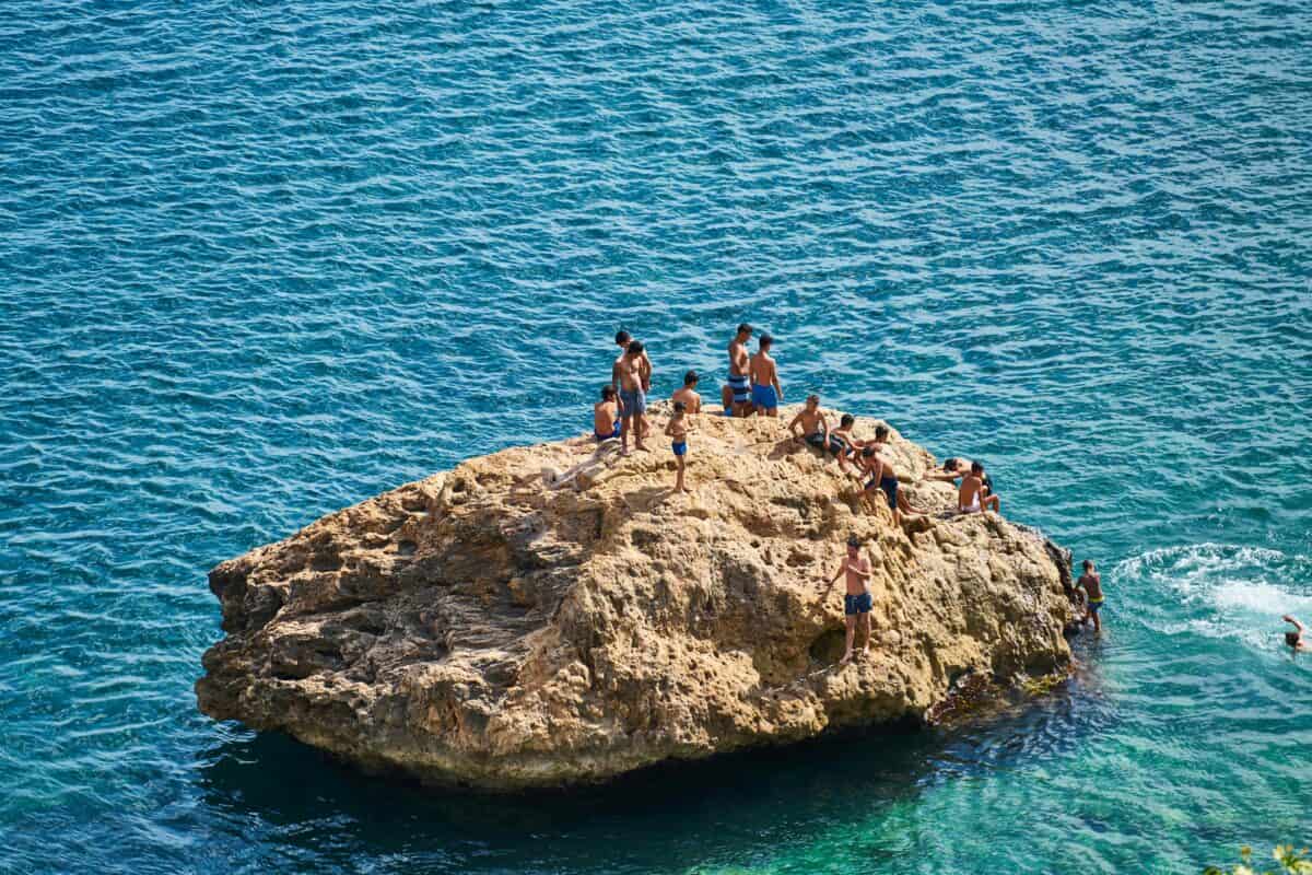A group of swimmers on top of a big rock.