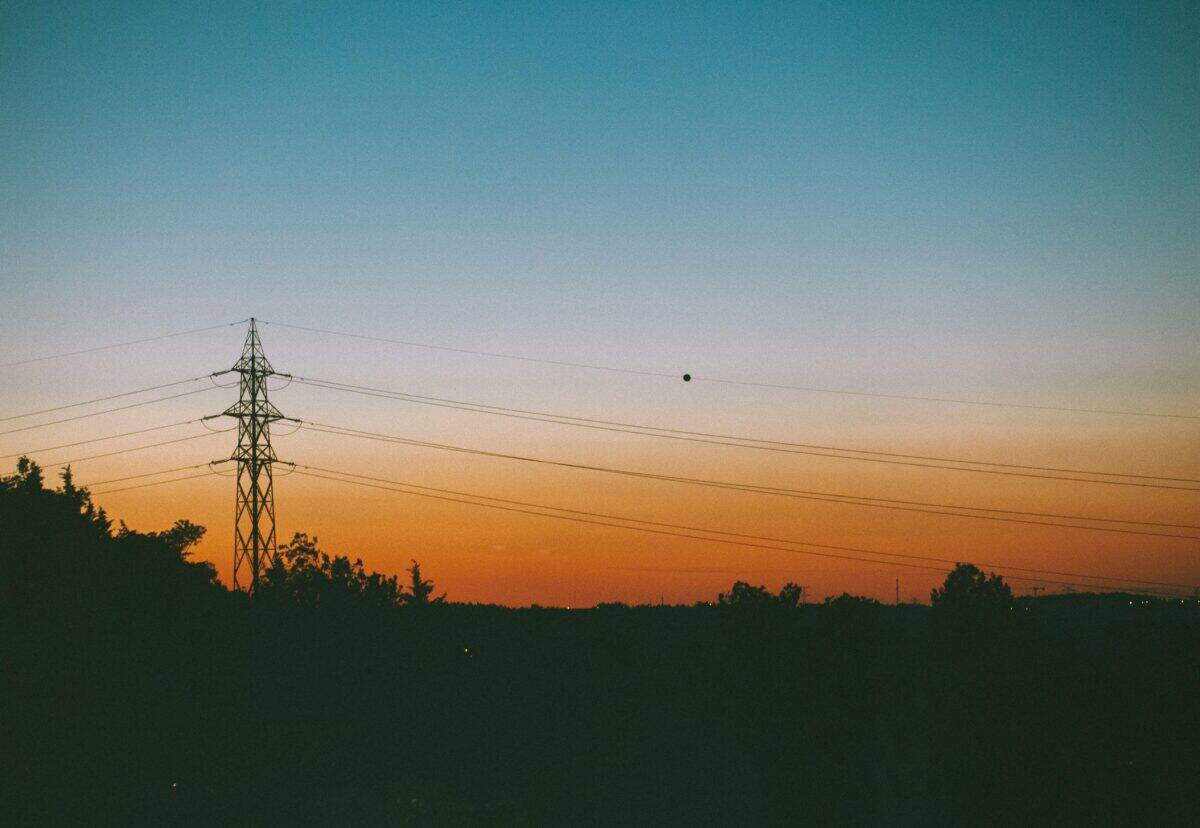 A silhouette of a town and its power grid at dusk.