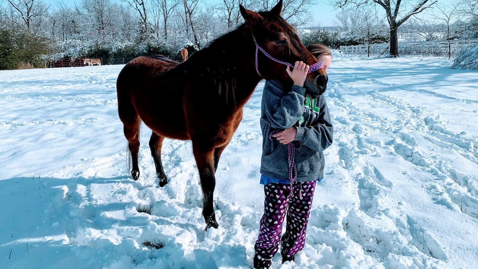 woman in white and black polka dot dress standing beside brown horse during daytime