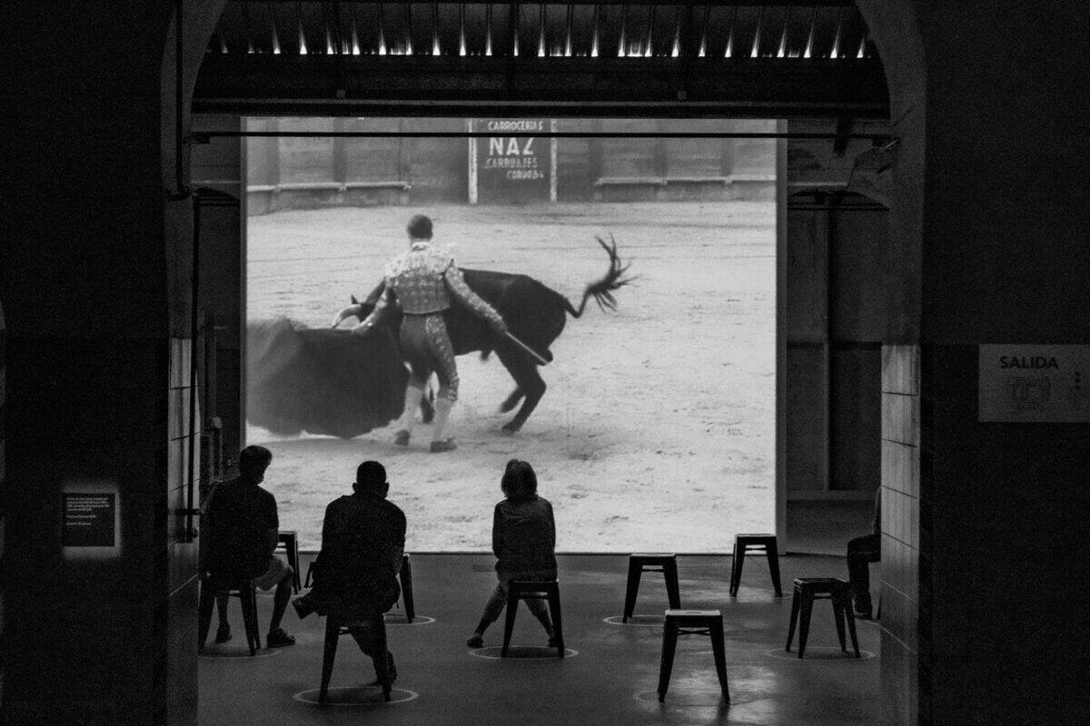 Silhouetted audience watching a bullfighting scene in an old cinema in Madrid, Spain.