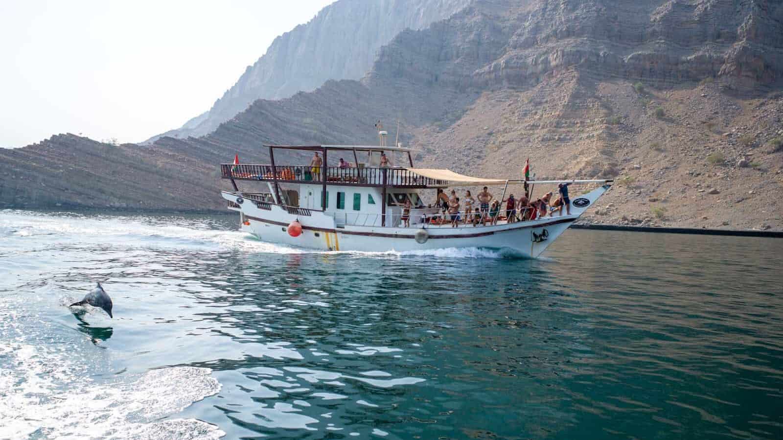 white boat on body of water near mountain during daytime