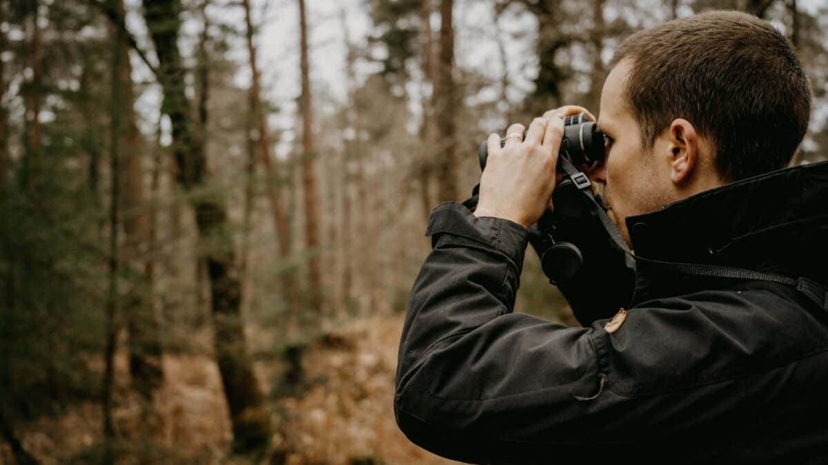 A man using a pair of binoculars to spot birds.