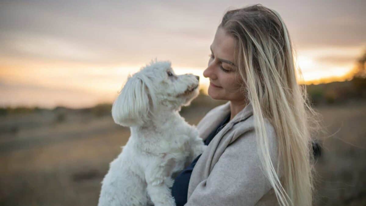 a woman holding a white dog in a field