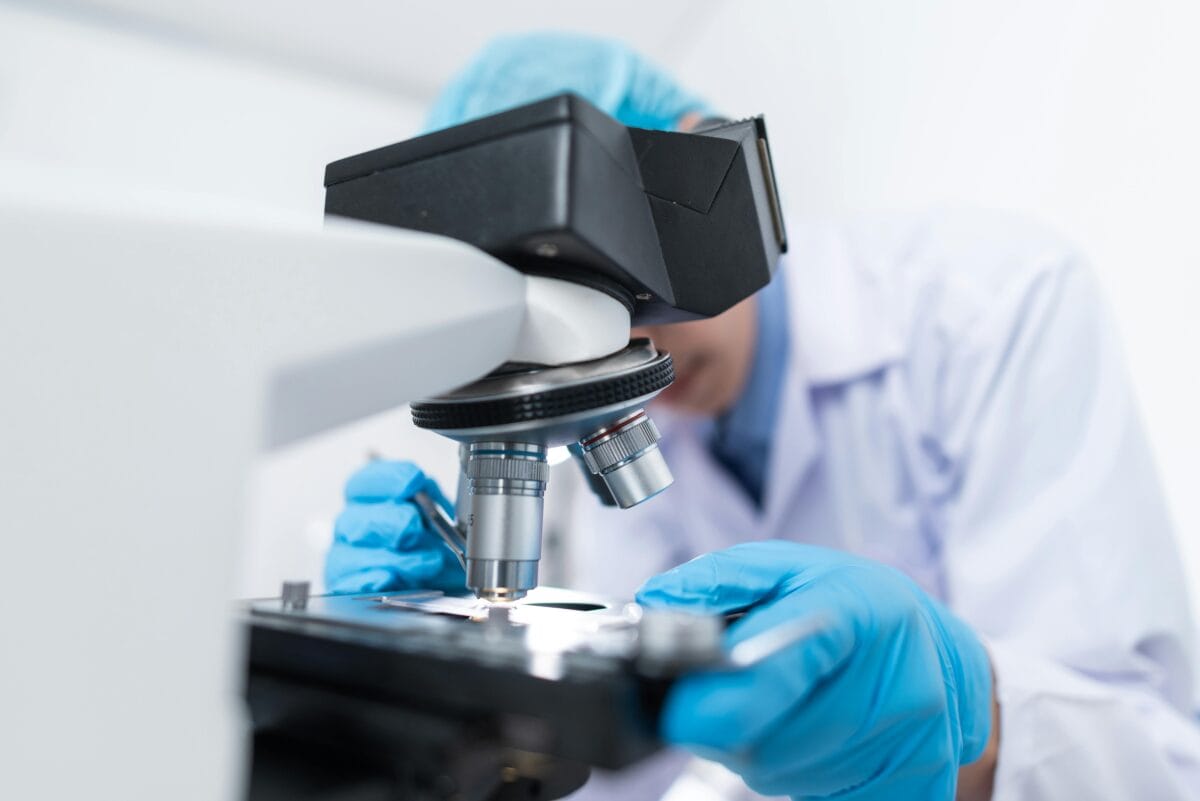 A professional peeking at a specimen on a microscope.