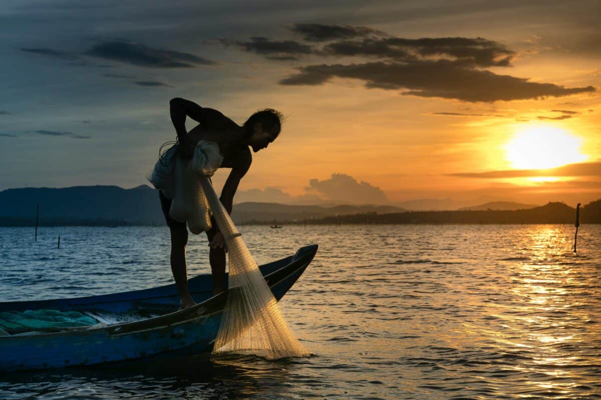 A silhouette of a fisherman while the sun sets.
