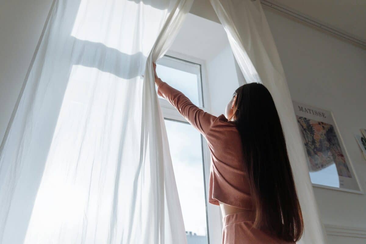 A woman trying to open the window of her room.
