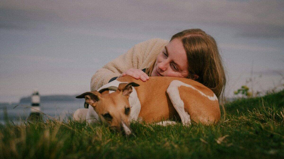 a woman laying in the grass with a dog