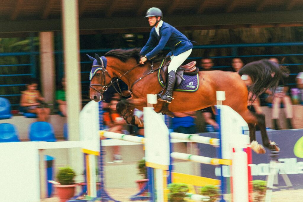A jockey in action during an equestrian jumping competition outdoors.