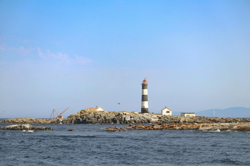 Race Rocks Lighthouse stands on a rocky island under a bright blue sky in Metchosin, British Columbia.
