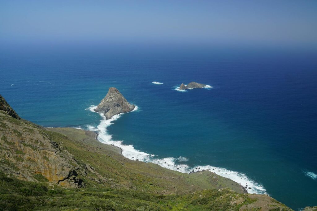 A breathtaking view of a rugged coastline and expansive ocean under a clear sky, ideal for travel inspiration.