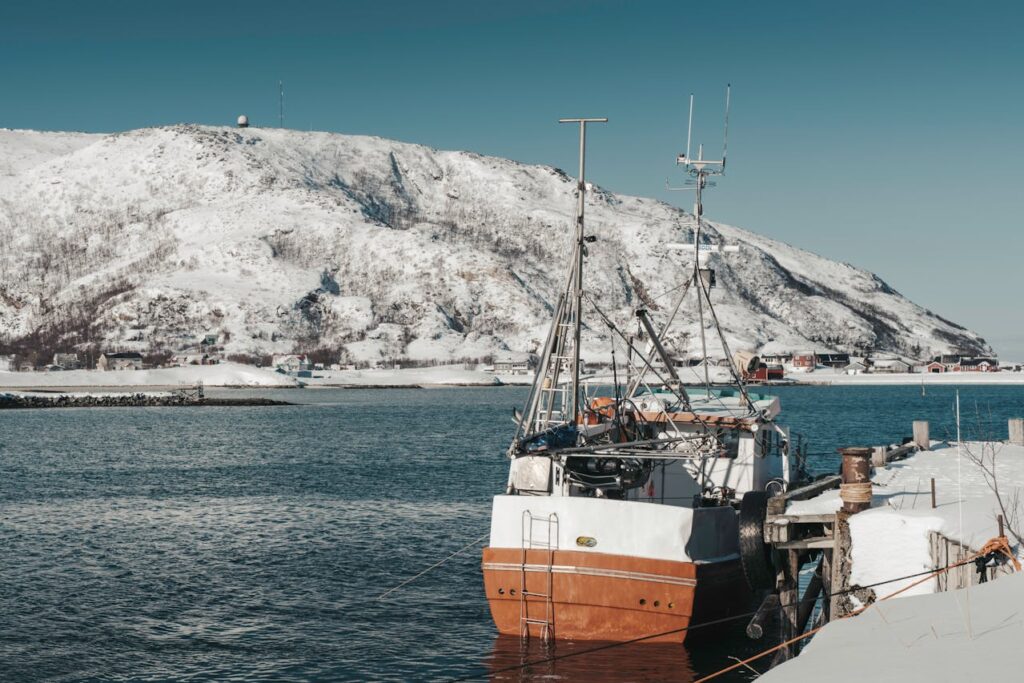 a fishing boat on still water surrounded by icy landscape