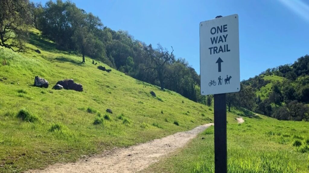 A one-way trail sign on a hillside, providing clear guidance for hikers to follow the designated path ahead.