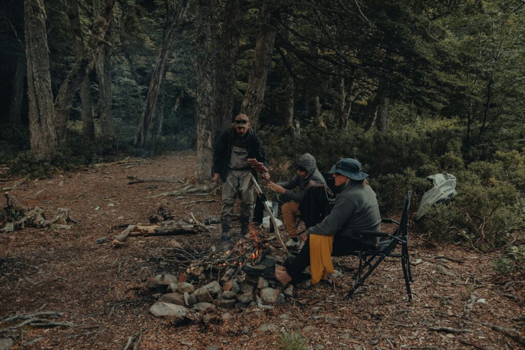 A cozy campfire scene with three people enjoying each other's company amidst the serene woods at night.